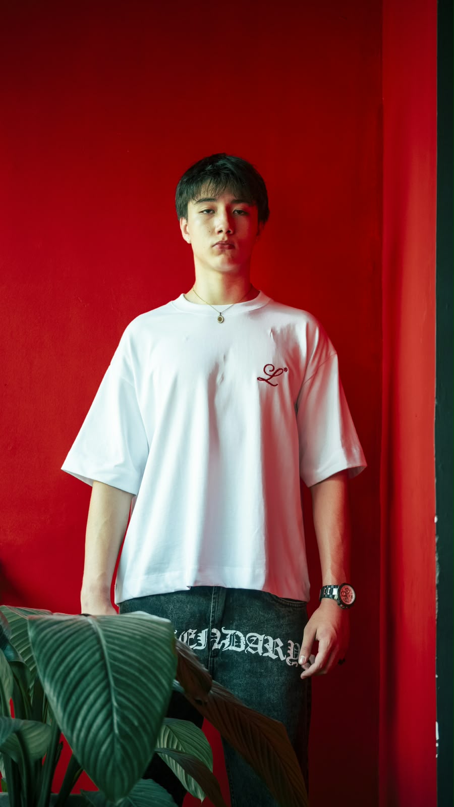 Modelo vistiendo camiseta blanca boxy fit Legendary Immortal God, con corte amplio y monograma L bordado en rojo.