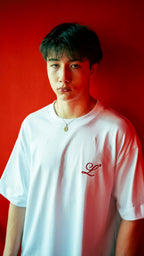 Modelo usando camiseta blanca boxy fit Legendary Immortal God con monograma L bordado en rojo en el pecho.