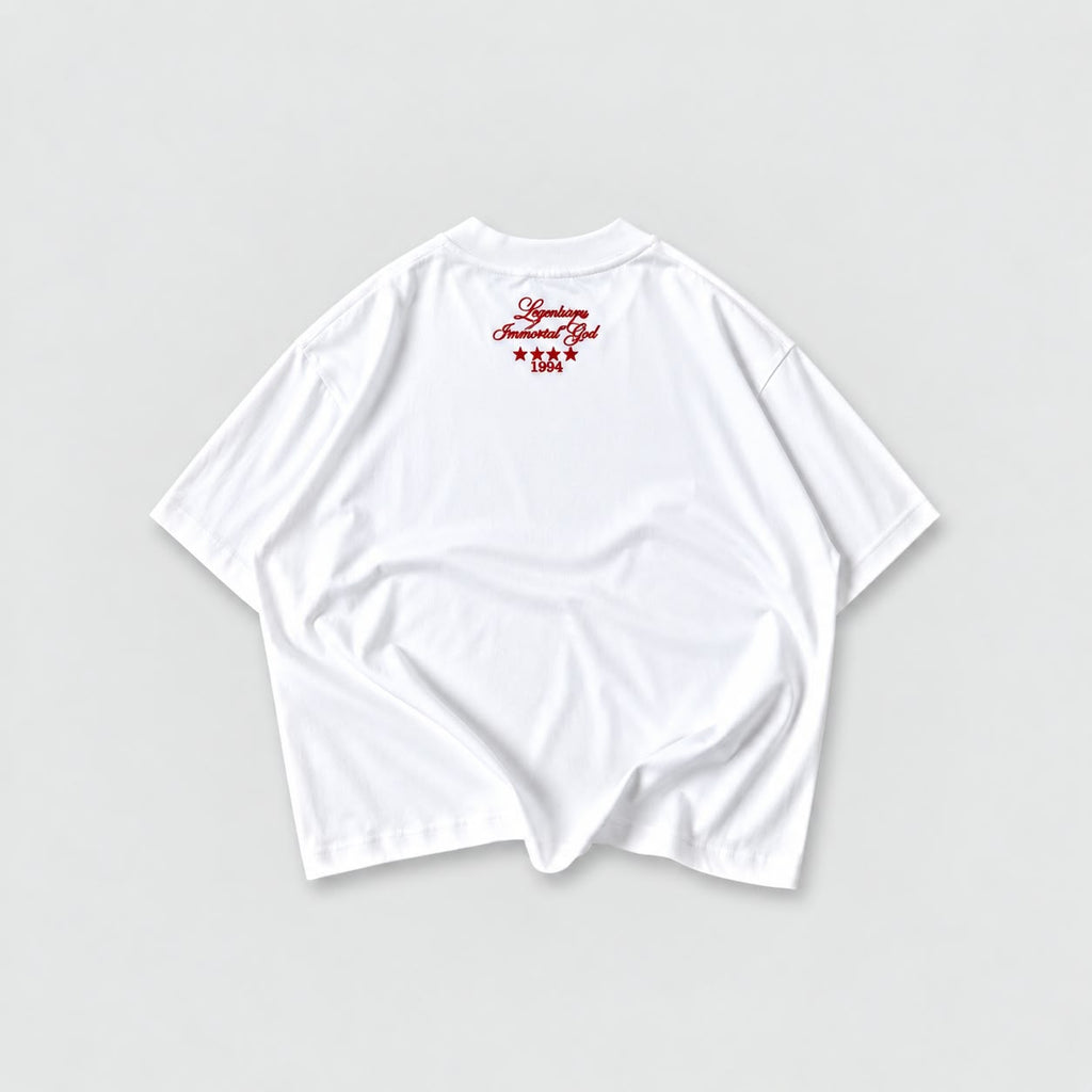 Camiseta blanca boxy oversize Legendary Immortal God con lettering rojo, estrellas y año 1994 en la espalda.