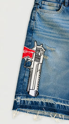 Bordado gráfico de pistola Legendary en short denim azul con acabado desgastado.