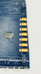 Detalle de short denim azul Legendary Mafia con bordados de proyectiles amarillos y acabado desgastado.