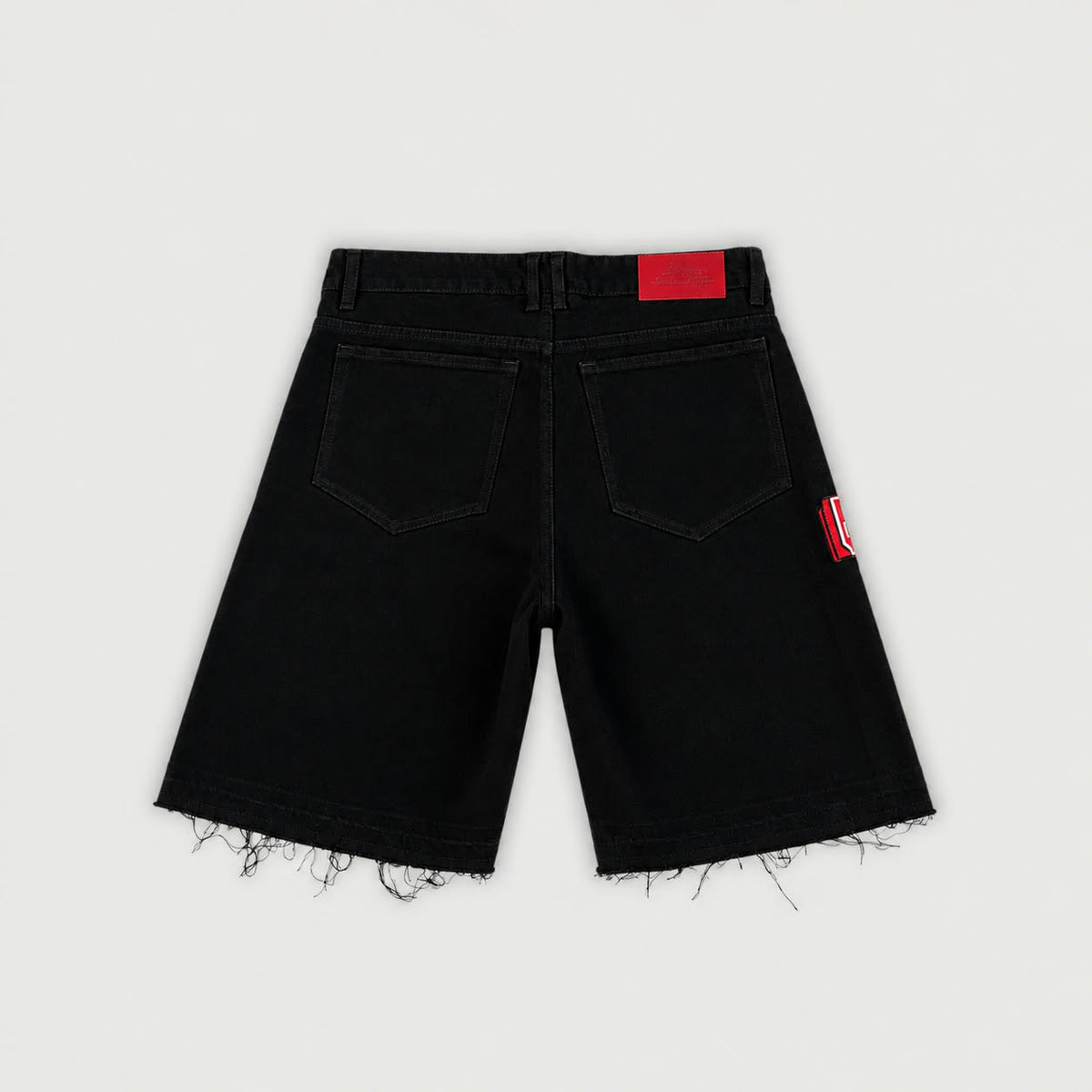 Vista posterior de short denim negro Legendary con bolsillos traseros, etiqueta roja y bajo deshilachado.